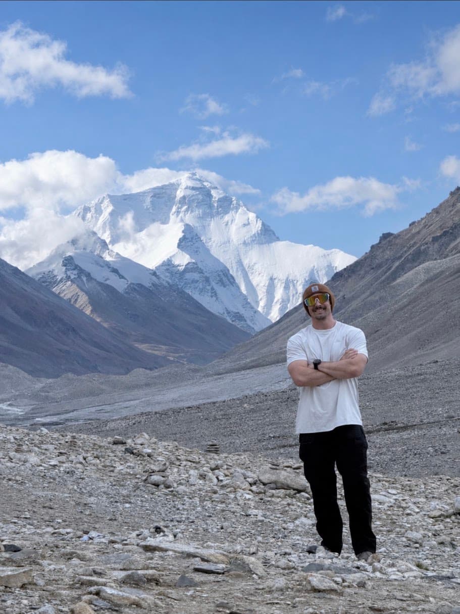 Sava Stosic standing in a rocky valley with a snow-covered mountain behind him.